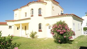A two-story building with a white facade and red-tiled roof. There are multiple windows with shutters, and a small garden area with pink flowers. - Luxury villa, with garden and private pool, A/C, free WiFi, near beach (Albufeira)