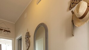 Une pièce comprenant une console en bois, un miroir, un chapeau accroché au mur et une corde décorative.