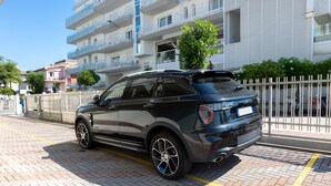 Un bâtiment moderne doté de balcons, d’une zone pavée et d’une voiture garée.