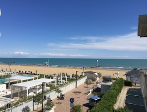 A beach view with a pool area, umbrellas, and a lifeguard tower.