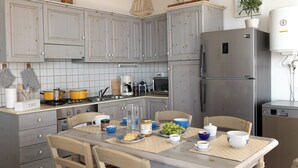 Une cuisine avec des meubles de couleur grise, un réfrigérateur en acier inoxydable et une table à manger mise avec des assiettes, des bols et des tasses.