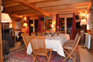 A wooden cabin interior with a dining table set for six, surrounded by wooden chairs.