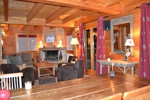 A cozy log cabin interior with a fireplace, wooden furniture, and a mirror with a decorative frame.