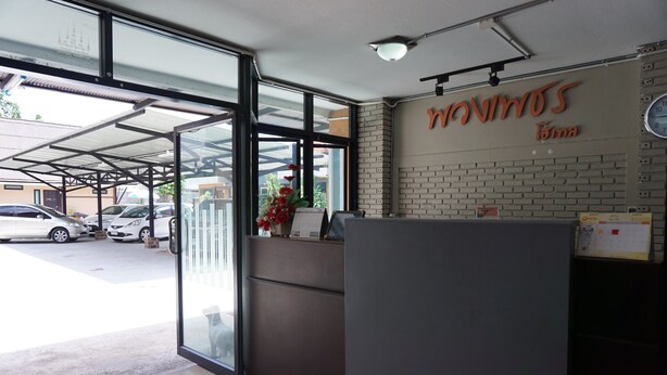 A reception area with a glass door, a reception desk, a clock, and a sign that reads "MAVIMOS Toma". - Puangpech Hotel (Lampang)