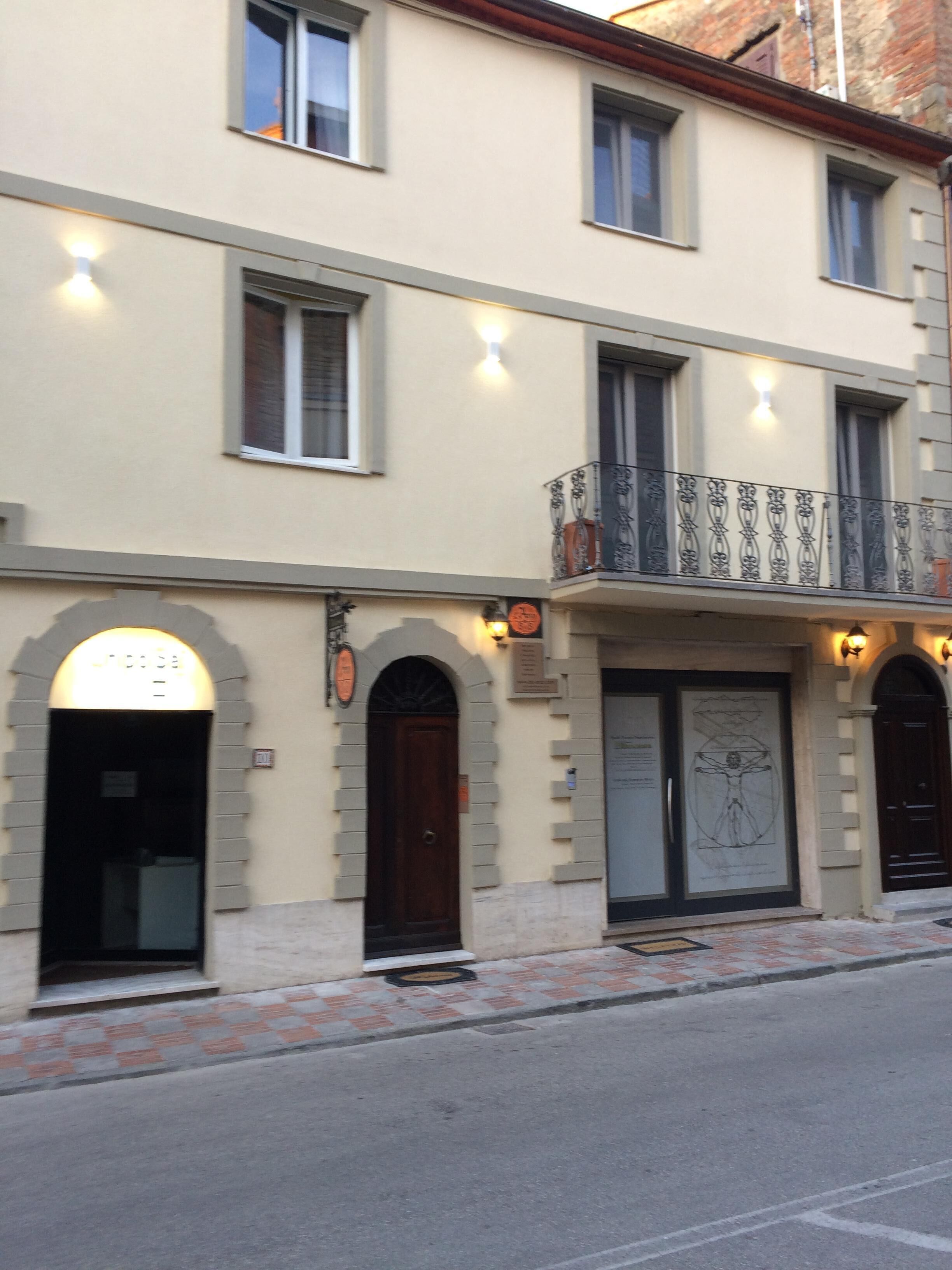 Ein Gebäude mit heller Fassade, mehreren Fenstern und einem Balkon mit aufwendigen Metallgeländern.