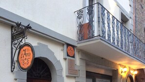A building with a wooden door, a balcony with ornate metal railings, and a sign that reads "Welcome".