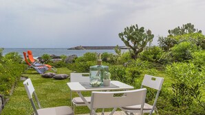 Un espace extérieur aménagé avec une table et des chaises, une bouteille en verre et un cactus.