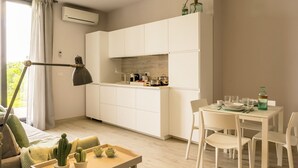 Une cuisine moderne avec des meubles blancs, une table à manger dressée pour quatre personnes et un cactus posé sur la table.
