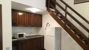 A kitchen with wooden cabinets, a microwave, a sink, and a refrigerator. - Terraced house in the shade of pine trees 500 meters from the beach.   (PULA)