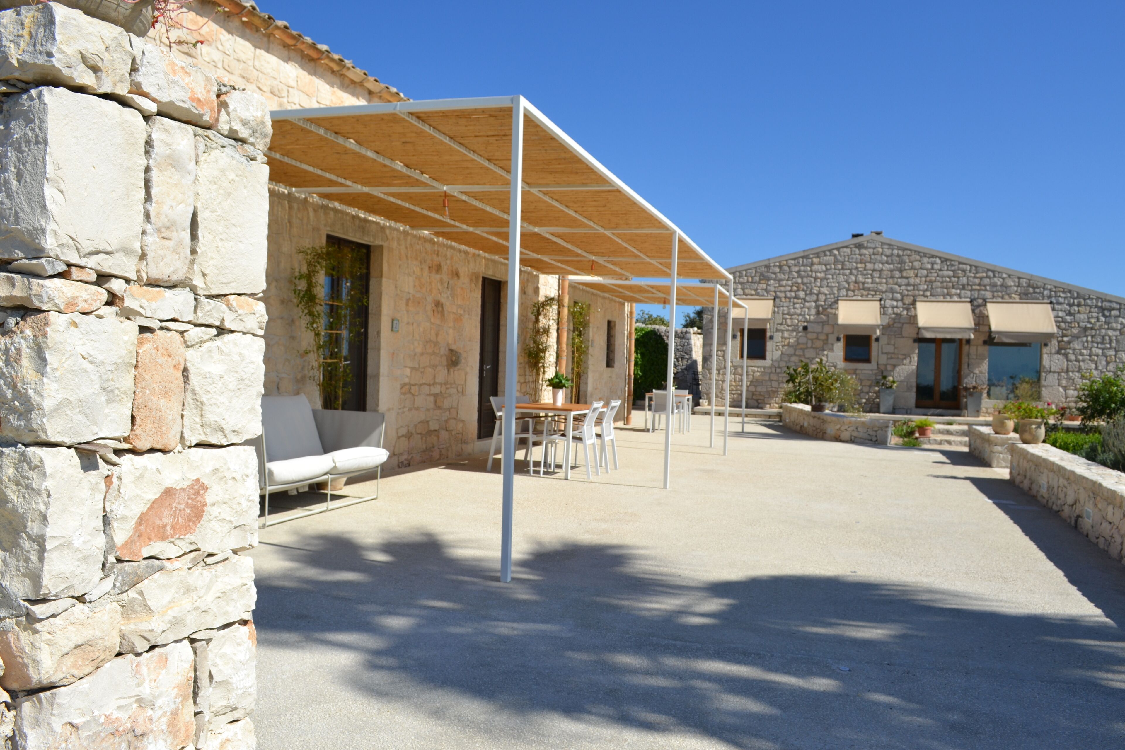 Un bâtiment en pierre doté d’un patio couvert, d’un espace extérieur aménagé pour s’asseoir et d’un mur en pierre.