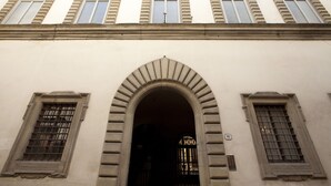 Fachada de edificio con cinco ventanales arqueados y una entrada central con un arco decorativo.