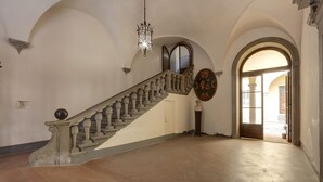 Una gran escalera con barandilla, un candelabro y una placa decorativa en la pared.
