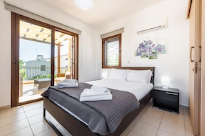 Une chambre d’hôtel avec un lit, une table de chevet, une commode, une fenêtre et une vue sur l’extérieur.