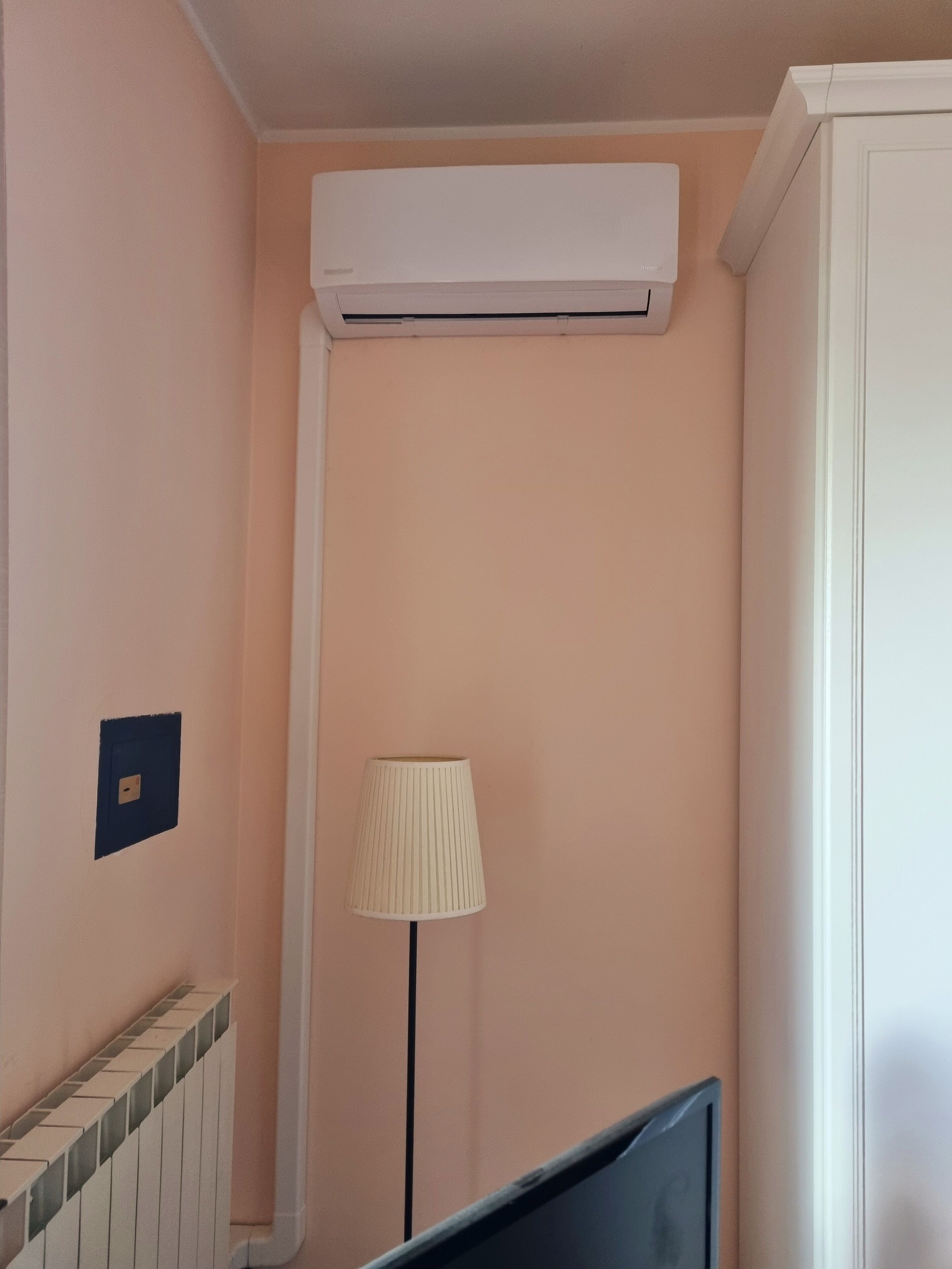 Una stanza con un condizionatore a muro bianco, una lampada e una scala con corrimano in piastrelle.