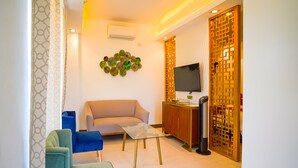 A modern living room with a sofa, two chairs, a coffee table, and a TV on a wooden cabinet. - Capital O Vaccinated Staff - OYO 785 The Greenhive (Ibaan)