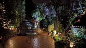 Un patio al aire libre con suelo de baldosas, una mesa redonda y un muro de piedra.