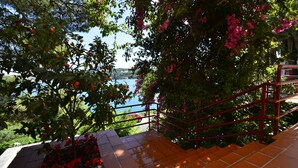 Una escalera con barandillas rojas que lleva a un balcón con vistas a un cuerpo de agua y exuberante vegetación.
