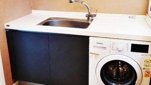 Une petite buanderie équipée d’un lave-linge encastré et d’un évier.