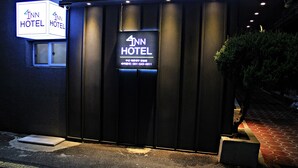 L’entrée du 4th Inn Hotel se distingue par sa façade sombre et son enseigne lumineuse.