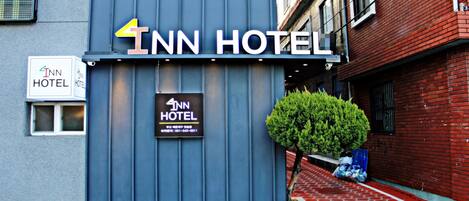 A 4th Inn Hotel with a blue facade, a small window, and a signboard with contact information.