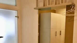 Ein modernes Interieur mit einem raumhohen Spiegelkleiderschrank, einer Tür mit Milchglasfüllung und einem Holzboden.