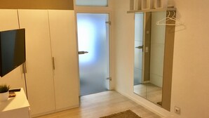 Ein modernes Schlafzimmer mit Kleiderschrank, Fernseher und Spiegel.