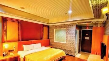 A hotel room with a large bed, a bedside table, a desk, and a patterned wall.