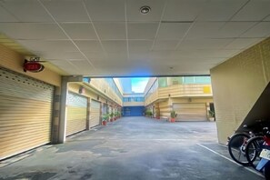 Un espace de stationnement couvert avec des portes de garage fermées, des plantes en pot et un porte-vélos.