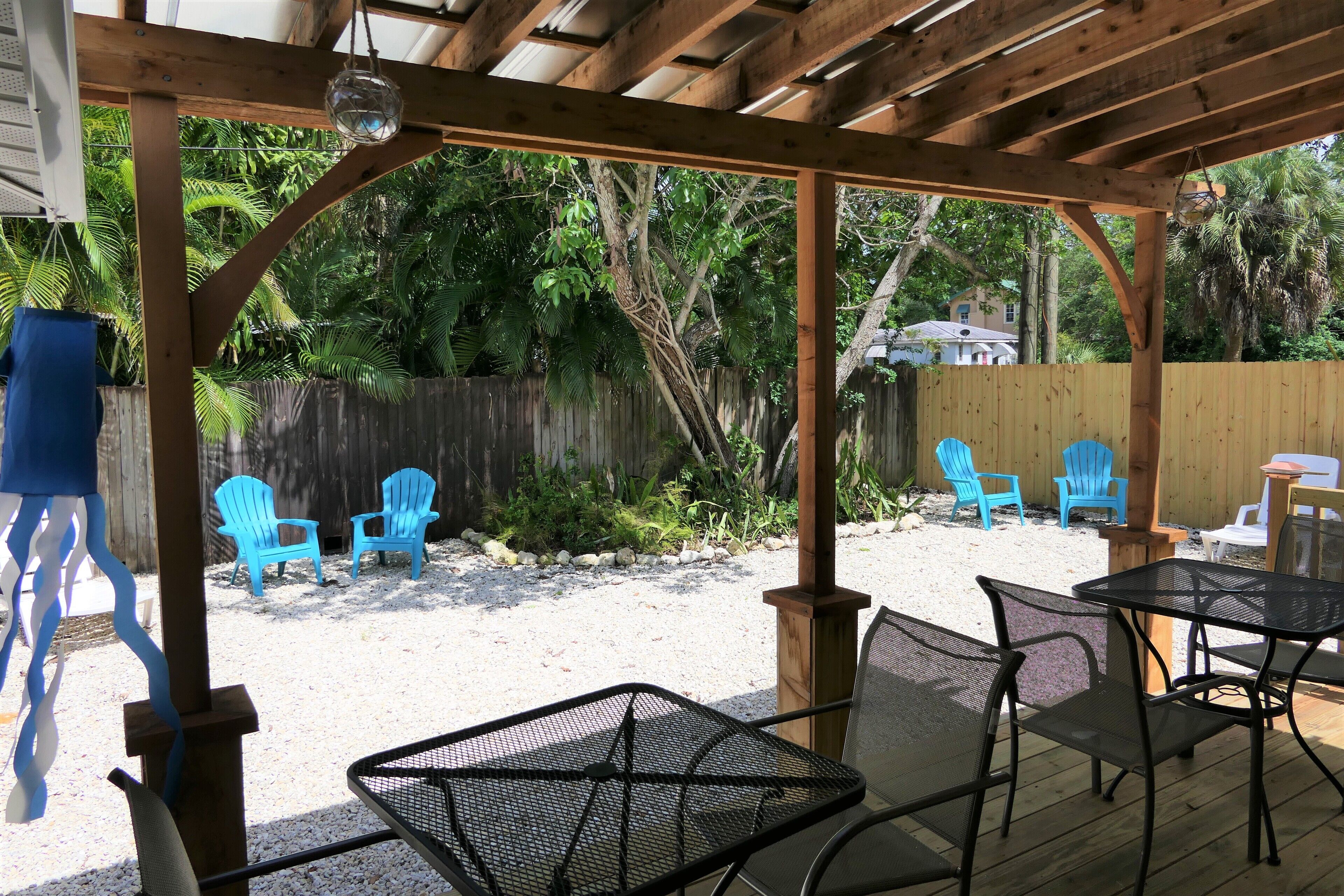 Un patio couvert agrémenté d’une pergola en bois, de chaises en métal et d’une table.
