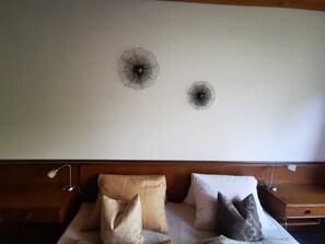 Et hotelværelse med en seng, to billeder på væggen og et natbord med en lampe.