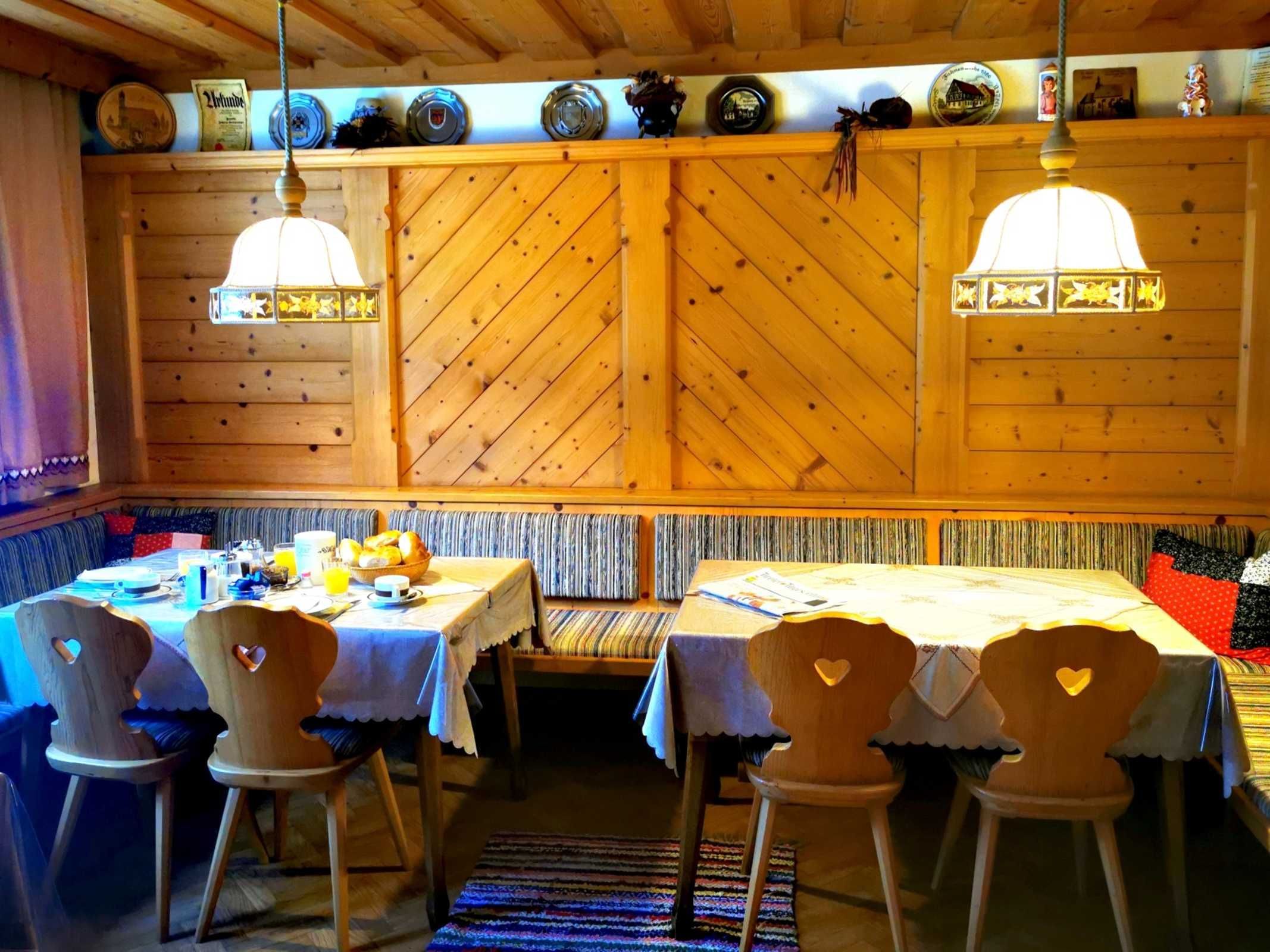 Un intérieur chaleureux en bois, avec un coin repas agrémenté de chaises en forme de cœur, d’un banc et d’une table dressée pour le petit-déjeuner.