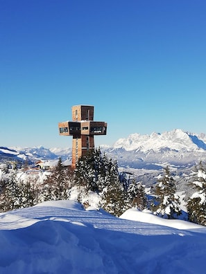 A snow-covered mountain landscape with a unique cross-shaped structure in the foreground. - Triple room (incl. Breakfast) - Weindlhof (Waidring)