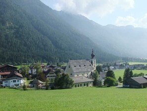 Ein ländliches Dorf mit Kirche, Häusern und einem Berg im Hintergrund.