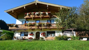 A traditional chalet with a sloped roof, wooden balconies with flower boxes, and a front entrance with a bench. - Double room 1 incl. extended breakfast (room no. 4) - Weindlhof (Waidring)