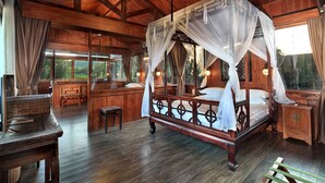 A wooden four-poster bed with a canopy, a wooden bench, and a small table in a room with large windows and a wooden ceiling. - Yangshuo Mountain Retreat (Guilin)