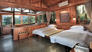 A wooden cabin with two beds, a bench, and large windows offering a view of the forest. - Yangshuo Mountain Retreat (Guilin)