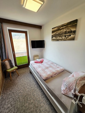 A bedroom with a bed, a chair, a TV, and a painting. - Single Room - Weindlhof (Waidring)