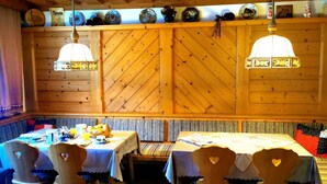 A cozy wooden interior with a dining area featuring heart-shaped chairs, a bench, and a table set with breakfast. - Single Room - Weindlhof (Waidring)