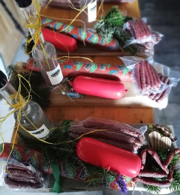 A display of various sausages and smoked meats, some wrapped in decorative paper and tied with yellow strings.