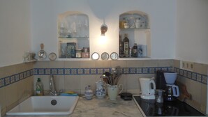 Una cocina con un fregadero, estufa y distintos utensilios sobre la encimera.