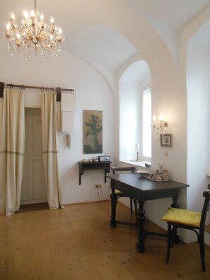 A dining area with a chandelier, a table, chairs, a painting, and a window with curtains. - Intimate and elegant atmosphere in the heart of Vienna (Wien)