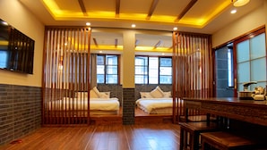 A hotel room with two beds, wooden floors, a dining table, and a TV mounted on the wall. - Putuo Memory Boutique Inn (Zhoushan)
