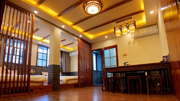 A hotel room with a wooden floor, a bed, a desk with chairs, and a window. - Putuo Memory Boutique Inn (Zhoushan)