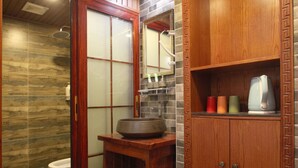 A bathroom with a wooden vanity, a sink, and a cabinet with a mirror. - Putuo Memory Boutique Inn (Zhoushan)