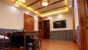 A room with a wooden dining table, chairs, a TV mounted on the wall, and a brick accent wall. - Putuo Memory Boutique Inn (Zhoushan)
