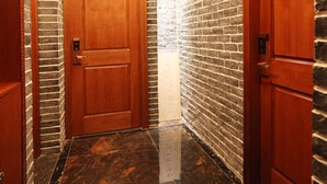 A hallway with wooden doors, brick walls, and a polished marble floor. - Putuo Memory Boutique Inn (Zhoushan)