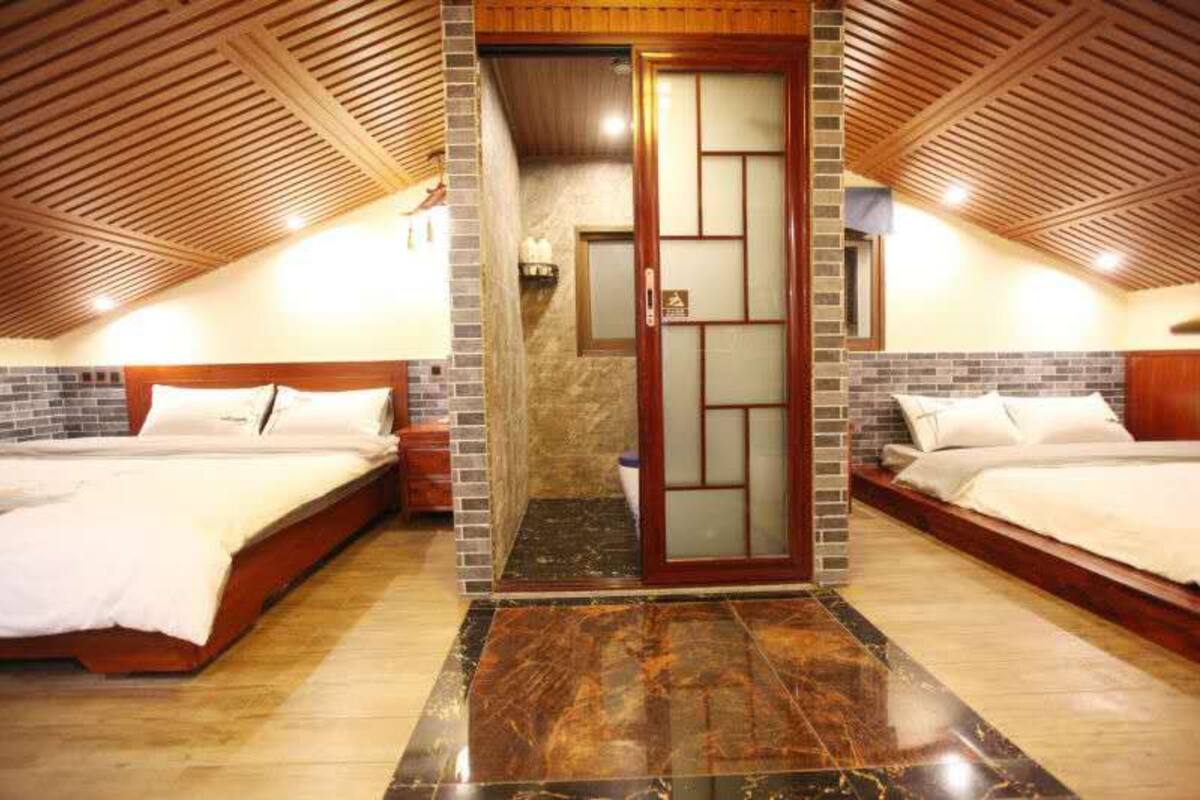 A hotel room with two beds, a wooden ceiling, and a tiled floor.
