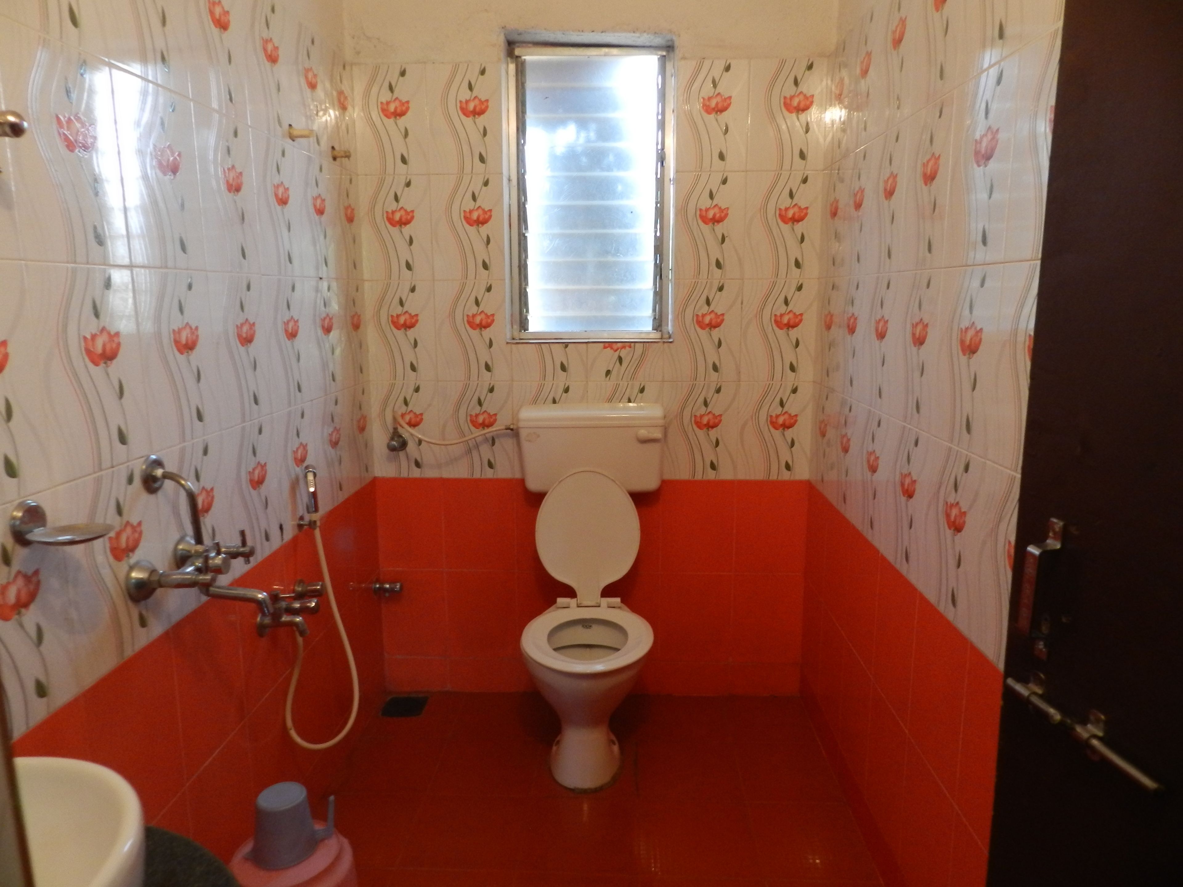 A bathroom with a toilet, a shower, and a window.