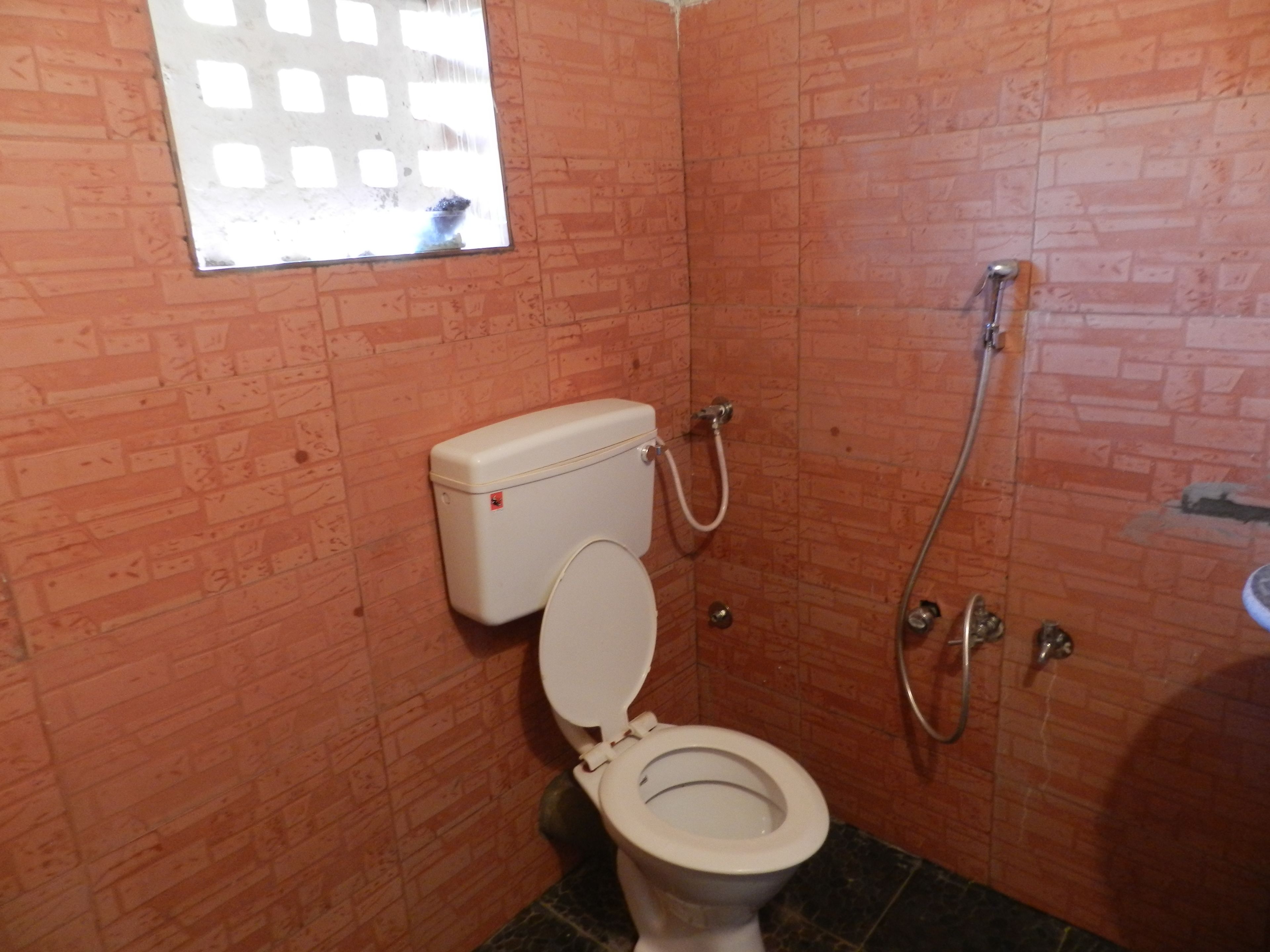 Un baño pequeño con inodoro, ducha y ventana.