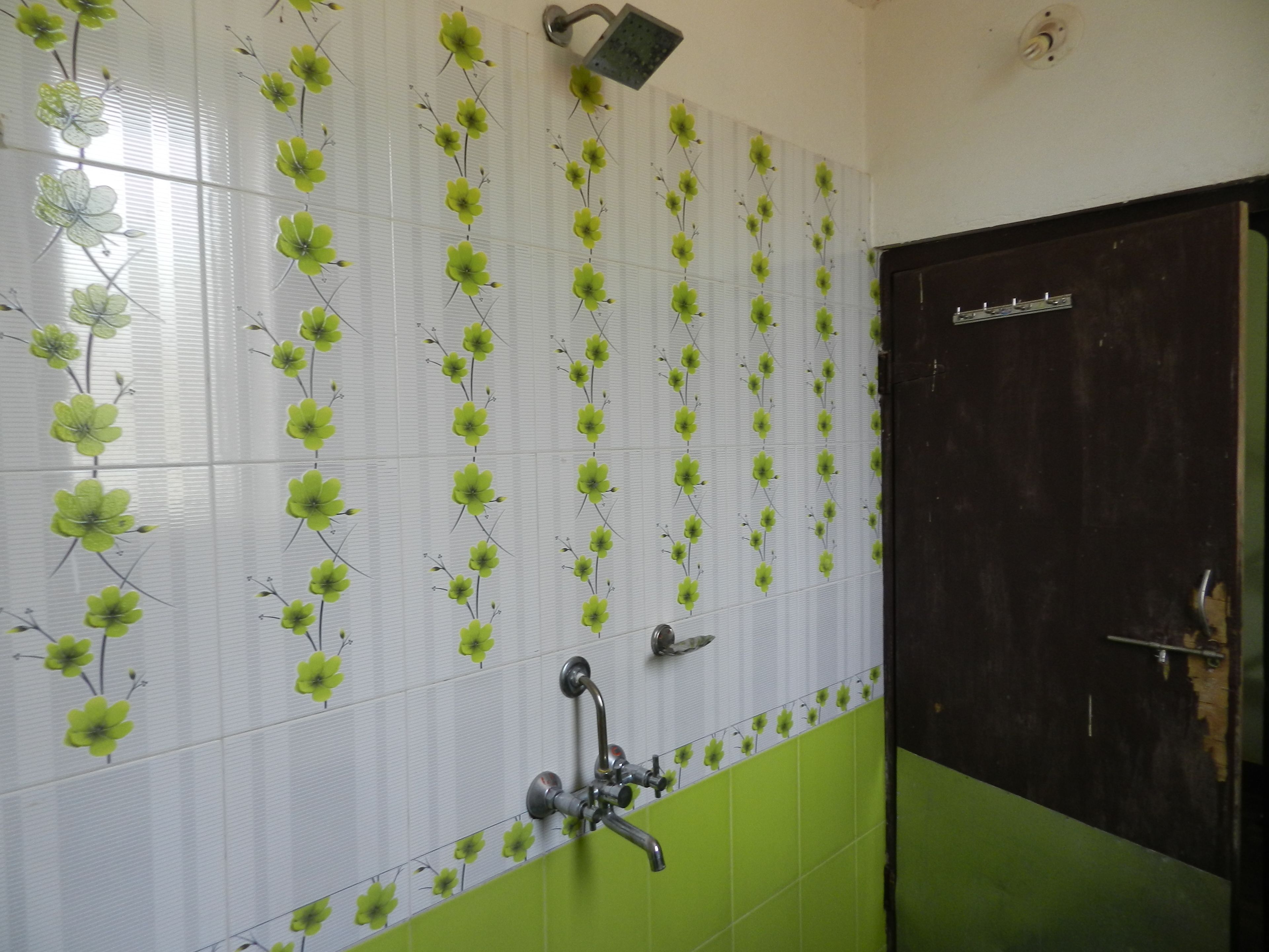 Un baño con azulejos verdes y blancos, una ducha y una puerta.